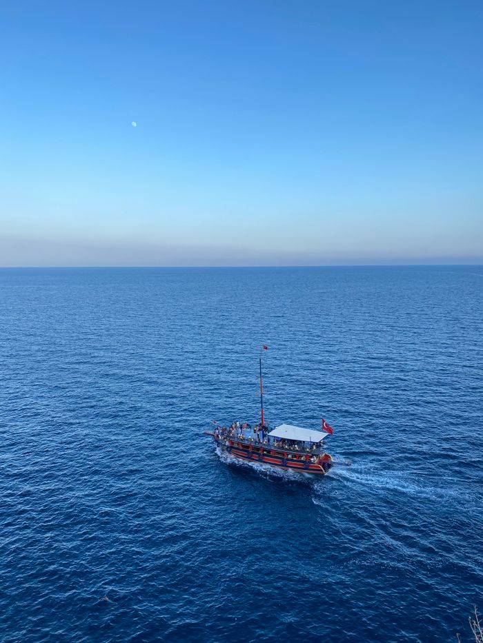 A small boat cruising under a clear blue sky, perfect for travel or tourism themes.